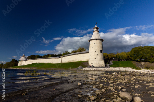 View of the Pskov Kremlin near the city river on a summer clear day. Trails for walking tourists.