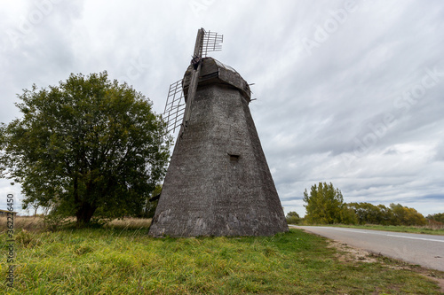 Old stone wooden windmill in an open field on a summer day in the Pskov region of Russia