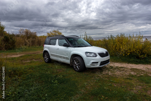 Universal white crossover car parked for travelers on the territories of coastal reserves in the Pskov region, west of the Izborsk Valley, Russia. Fishing, Hunting and Tourism © HAMERCAT