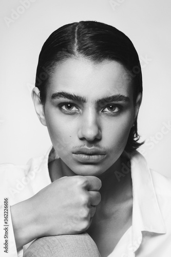 Vintage style black and white portrait of young beautiful tomboy with painted moustache photo