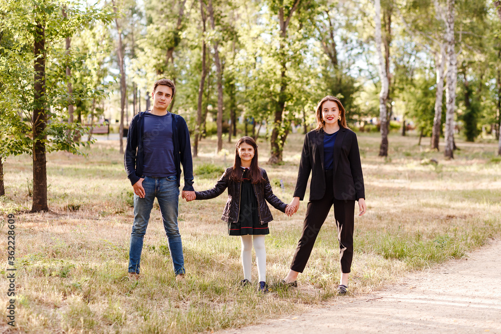 family of three children on a walk in the park in the summer. brother and two sisters hold hands family of three children on a walk in the park in the summer. brother and two sisters hold hands