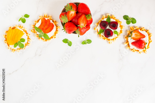 Top view of traditional Belgian waffles with soft cheese, fruits and berries with copy space.