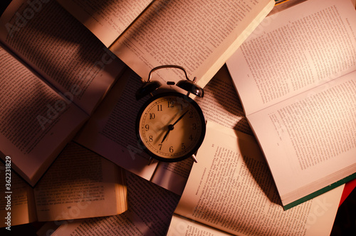 Books background with an old black clock on top