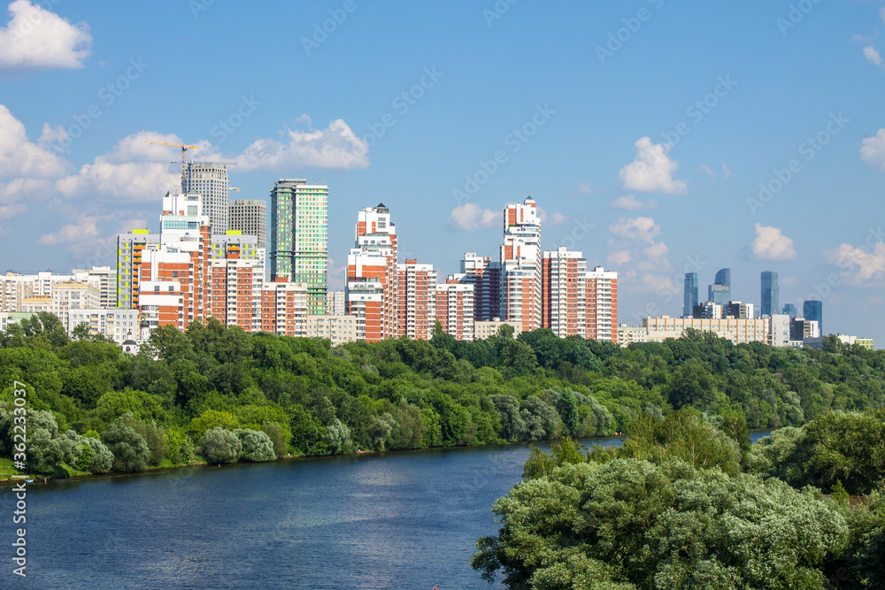 Panoramic view of modern residential buildings in Moscow Russia a Sunny summer day with green trees and moscow river with boat and copy space