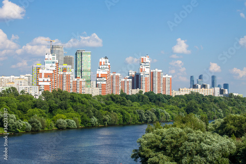 Panoramic view of modern residential buildings in Moscow Russia a Sunny summer day with green trees and moscow river with boat and copy space