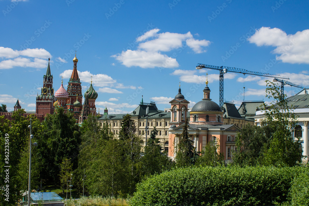panoramic view of the brick wall and the Kremlin towers and skyscrapers of Moscow city in the background on the blue sky and the Moscow river on a clear summer day