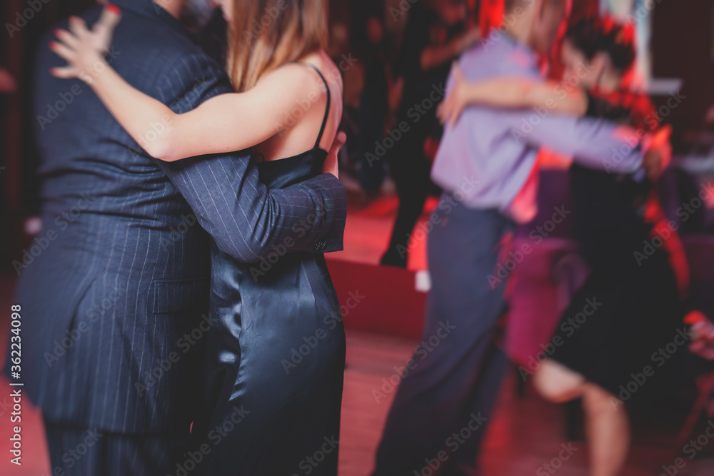 Couples dancing argentinian dance milonga in the ballroom, tango lesson in the red lights, dance festival Couples dancing argentinian dance milonga in the ballroom, tango lesson in the red lights, dance festival