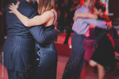 Couples dancing argentinian dance milonga in the ballroom, tango lesson in the red lights, dance festival © tsuguliev