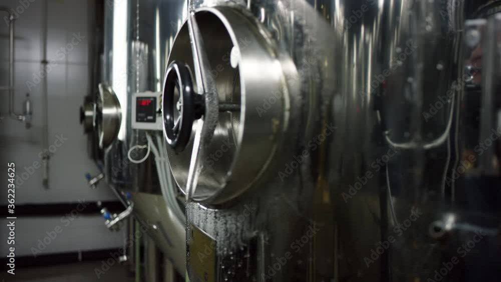 A row of several metal tanks standing next to each other, producing ale. A still side view slow motion close up A row of several metal tanks standing next to each other, producing ale. A still side view slow motion close up