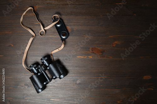 Old black military binocular on wood table background. Copy space for your text. Flat lay.