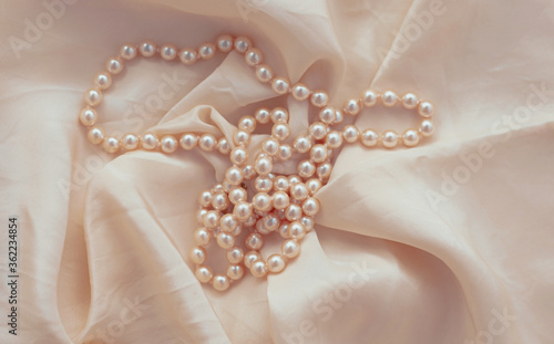 Pearl necklace on beige fabric.
