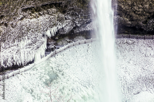 South Falls at Silver Falls State Park after a snow and ice storm - near Silverton  Oregon.  The fence and trail behind the falls are coated with ice.