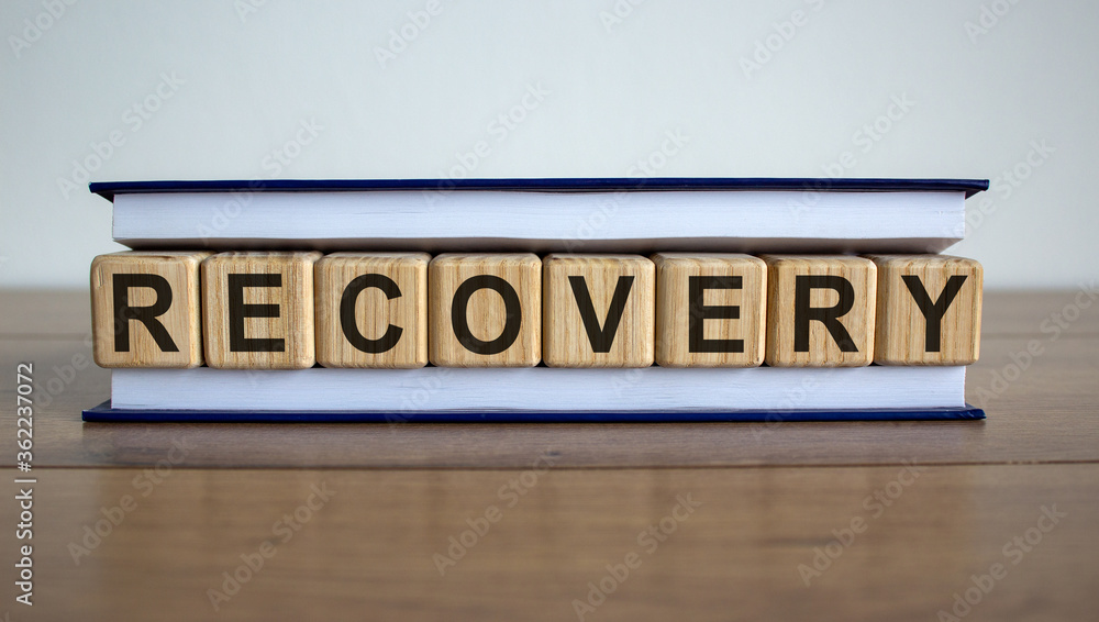 Concept word 'recovery' on wooden circles between pages of a book on a beautiful wooden table. White background. Business concept. Concept word 'recovery' on wooden circles between pages of a book on a beautiful wooden table. White background. Business concept.