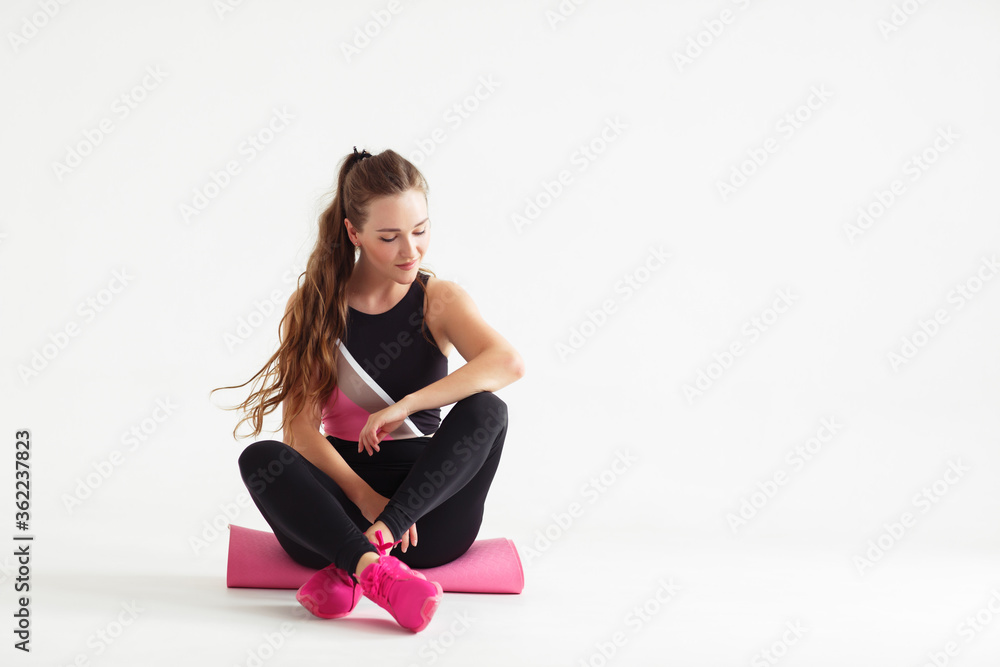 Smiling multiracial female yogi girl sit on rubber mat before yoga class, happy woman waiting for pilates training in white fitness studio. sport center banner for website header design. Smiling multiracial female yogi girl sit on rubber mat before yoga class, happy woman waiting for pilates training in white fitness studio. sport center banner for website header design.