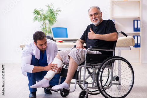 Old injured man visiting young male doctor traumatologist