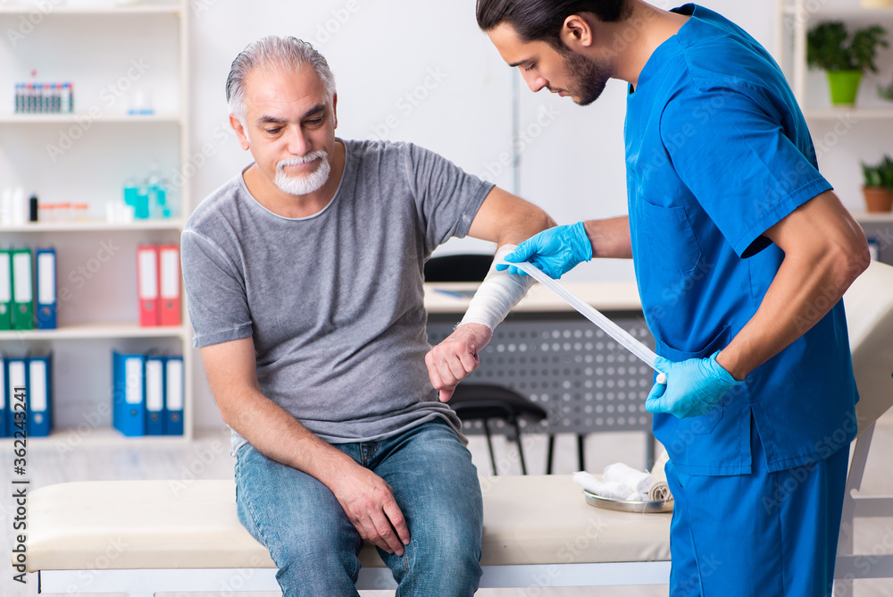 Young male doctor and old patient in first aid concept Young male doctor and old patient in first aid concept