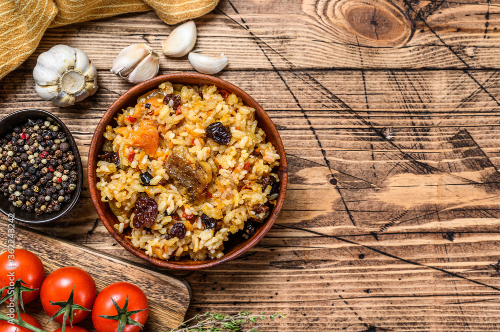 Pilaf in a wooden bowl. Central Asian cuisine Plov.  Wooden background. Top view. Copy space