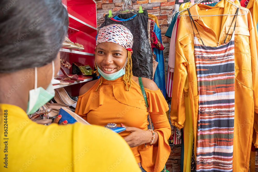 young african woman shopping in a local boutique shop, smiling and talking to someone