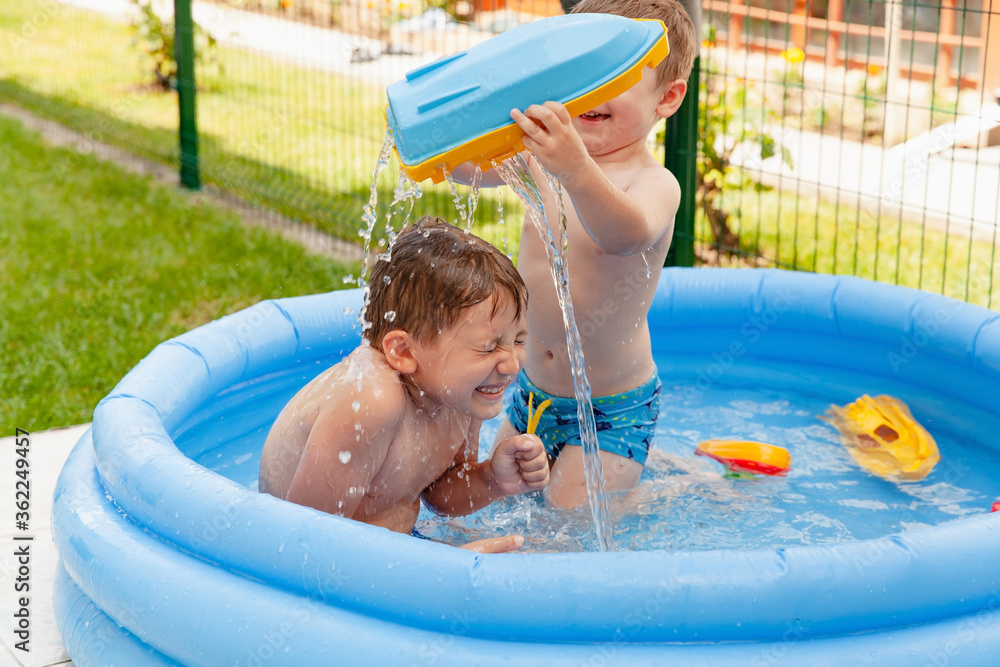 Two children with toys at swimming pool. Joyful kid playing in inflatable  pool on the backyard. Little kids at swimming pool on sunny day. Healthy  kids summer activity. фотография Stock | Adobe