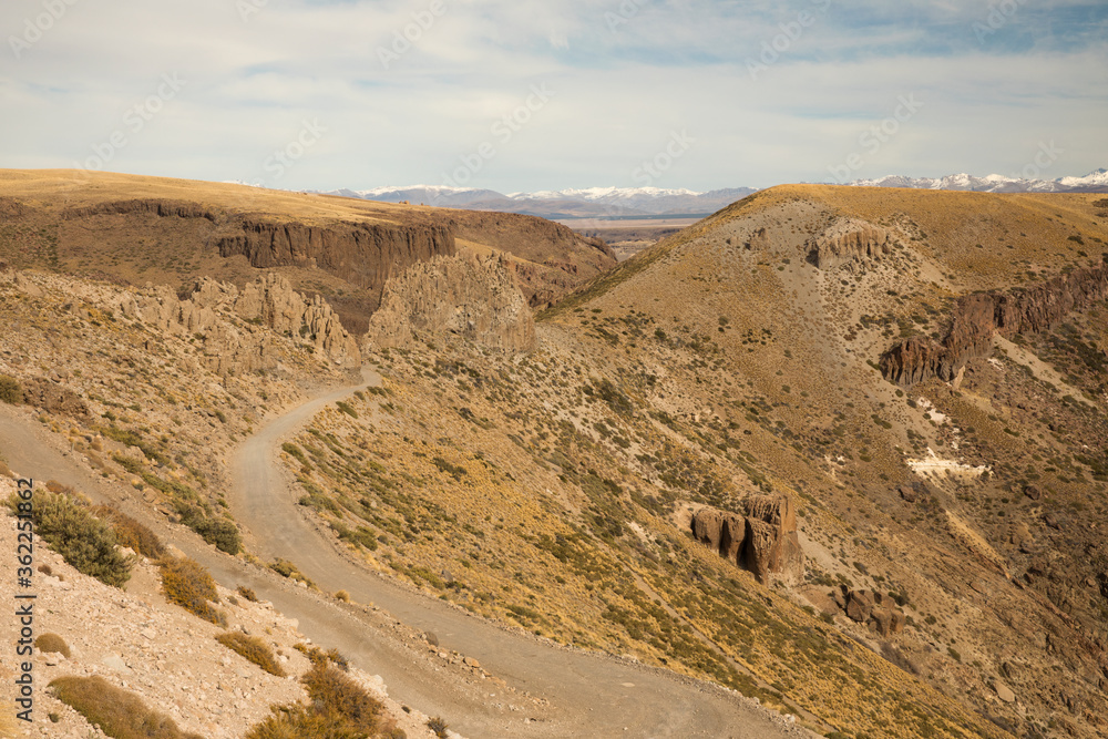 Adventure. Dirt road high in the mountains across the golden valley and yellow meadow. 