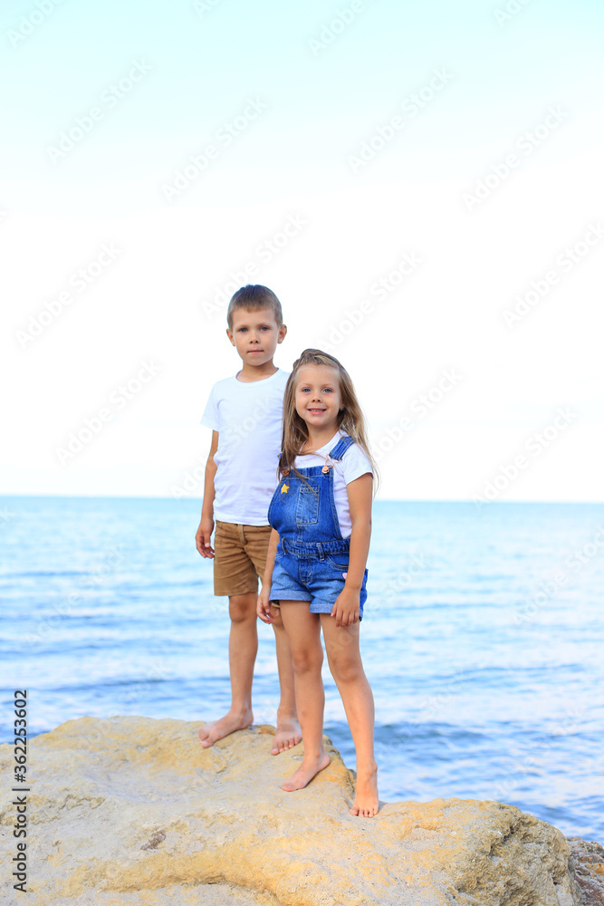 Two children are on the rocks by the sea Two children are on the rocks by the sea