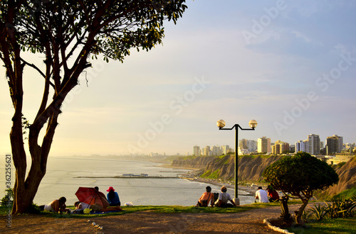 People looking at the coastline in Lima at sunset, photo