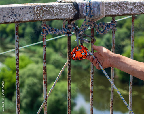 Concept of Extreme Sports and Fun. The man is making ropes and lifting gear ready for doing rope jumping from the bridge.