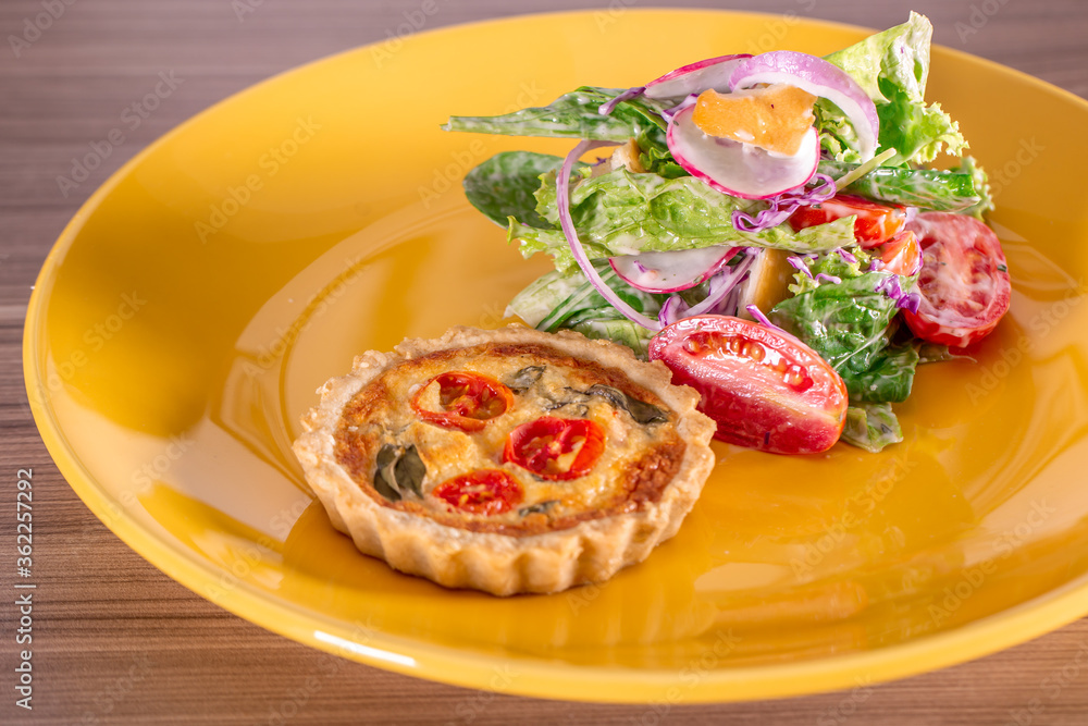 delicious quiche with salad, served in yellow dishes