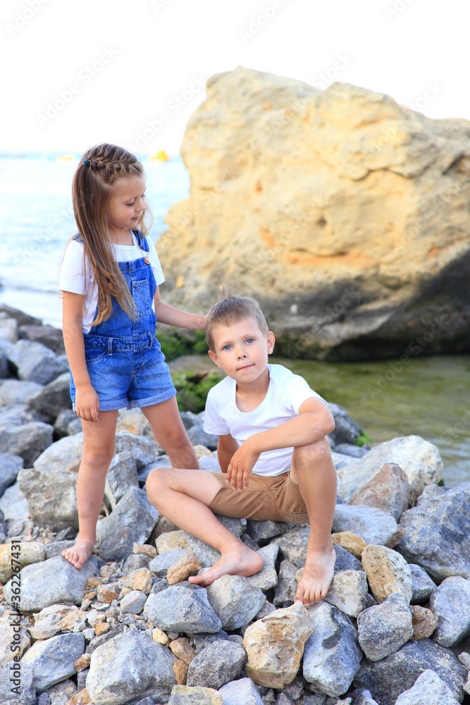 Two children are on the rocks by the sea