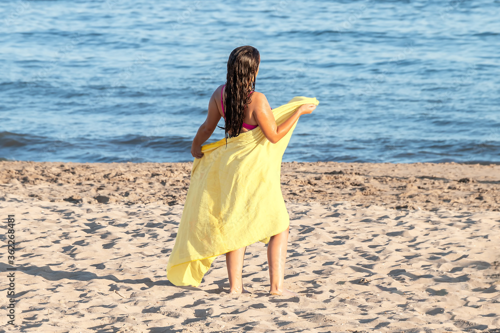 Young woman with yellow beach towel during vacation Young woman with yellow beach towel during vacation