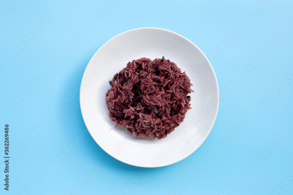 Black sticky rice on white ceramic dish on blue background. Black sticky rice on white ceramic dish on blue background.