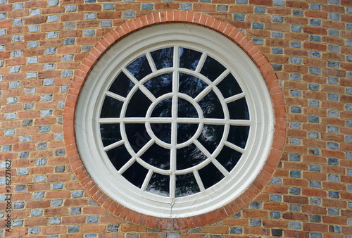 Round window with white frames surrounded by red bricks