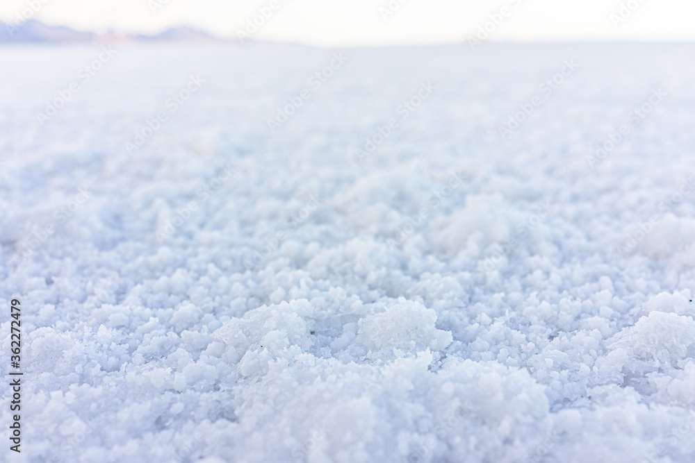 Closeup macro low angle ground level view of texture of Bonneville salt flats with wet salt on ground abstract with horizon in background