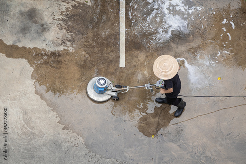 Worker washing and cleansing the concrete floor.