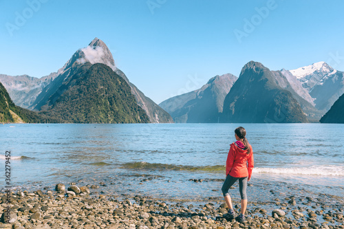 New Zealand - tourist couple hiking looking at Milford Sound enjoying iconic view and famous tourist destination in Fiordland National Park, South Island, New Zealand.
