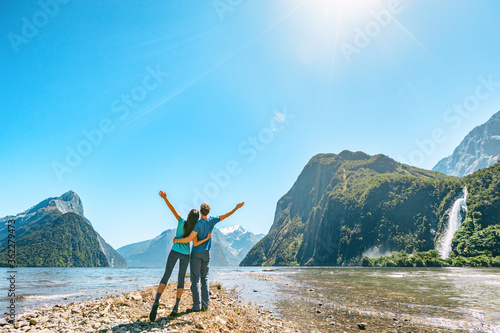 Outdoor couple happy with arms outstretched in Milford Sound New Zealand in nature enjoying active outdoor lifestyle hiking in Milford Sound, New Zealand by Mitre Peak in Fiordland. photo