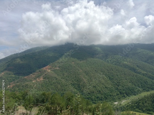 Clouds are flying at the top of green hill at the morning time