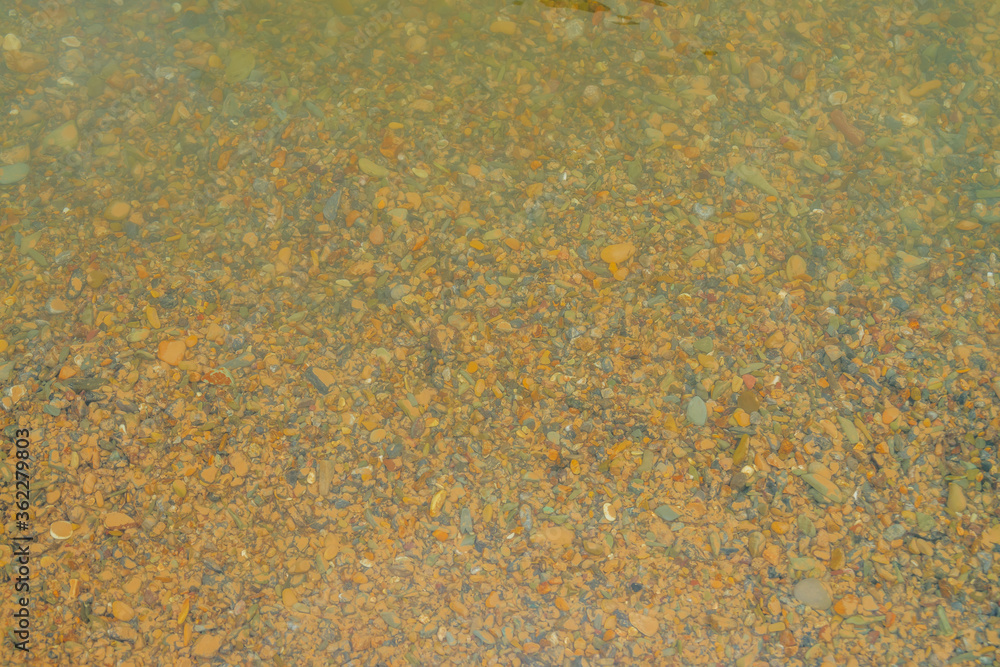 Many smooth stones on yellow sandy bottom of mountain river. Nature background of yellow clay bottom with pile smooth stones closeup. Natural texture of boulders in clear water of mountain creek. Many smooth stones on yellow sandy bottom of mountain river. Nature background of yellow clay bottom with pile smooth stones closeup. Natural texture of boulders in clear water of mountain creek.