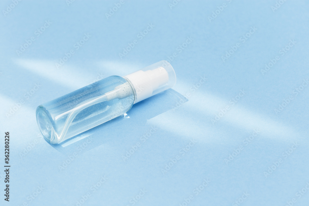 Small bottle with transparent cosmetic product, gel or crem on blue colored background. Flack with moisturizer for self-care. Monochrome image. Small bottle with transparent cosmetic product, gel or crem on blue colored background. Flack with moisturizer for self-care. Monochrome image.