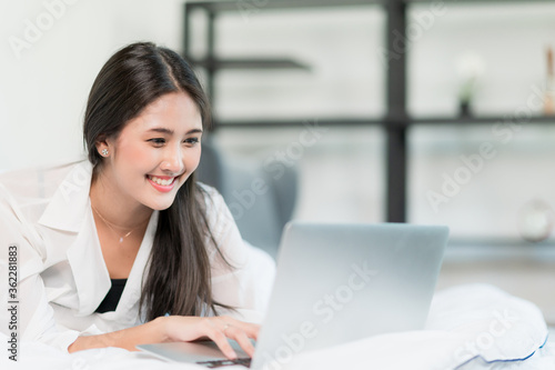 Young beautiful asian woman works from home with laptop computer at the the bedroom. Video conference concept.