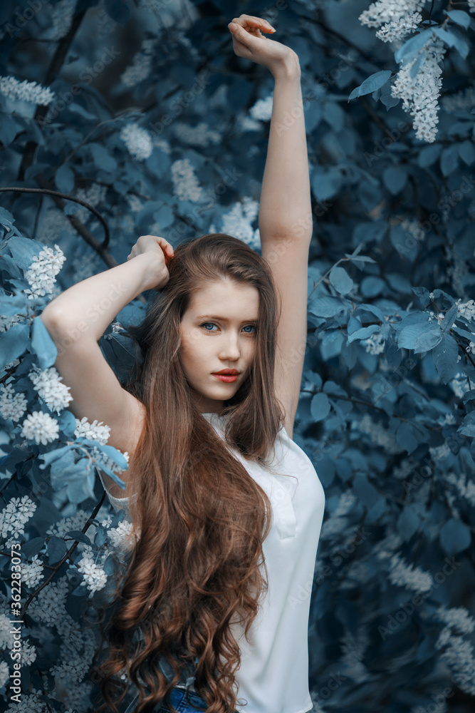 Portrait of woman on a background of blooming bird cherry.