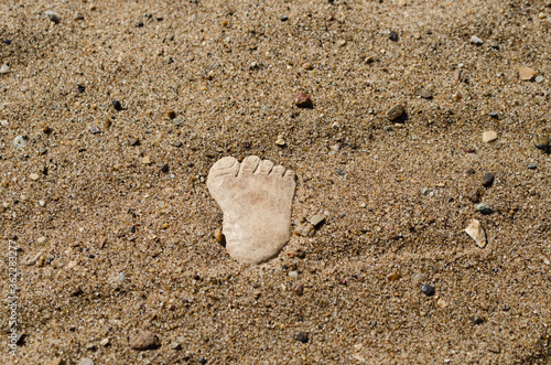 sandy beach with a fake footprint that is carved out of stone