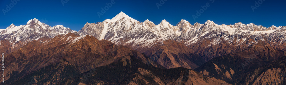Panoramic view of Snow cladded Panchchuli peaks falls in great Himalayan mountain range and alpine grass meadows at small hamlet Munsiyari, Kumaon region, Uttarakhand, India.