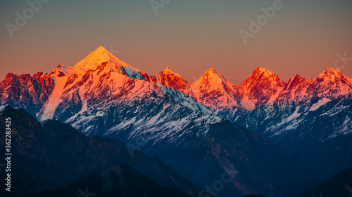 Panoramic view during sunset over snow cladded Panchchuli peaks falls in great Himalayan mountain range from small hamlet Munsiyari, Kumaon region, Uttarakhand, India.