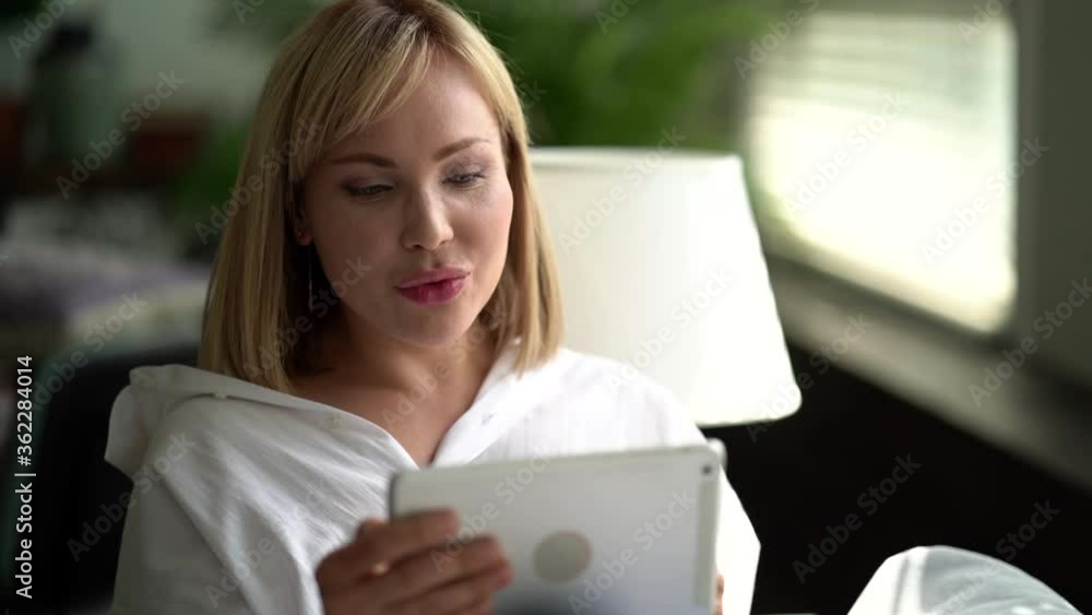 pretty woman is chatting by video call on tablet, resting at home on couch, distant communicating pretty woman is chatting by video call on tablet, resting at home on couch, distant communicating
