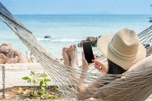 ัyoung women touch screen smart phone on cradle at the beach include path on screen of smartphone