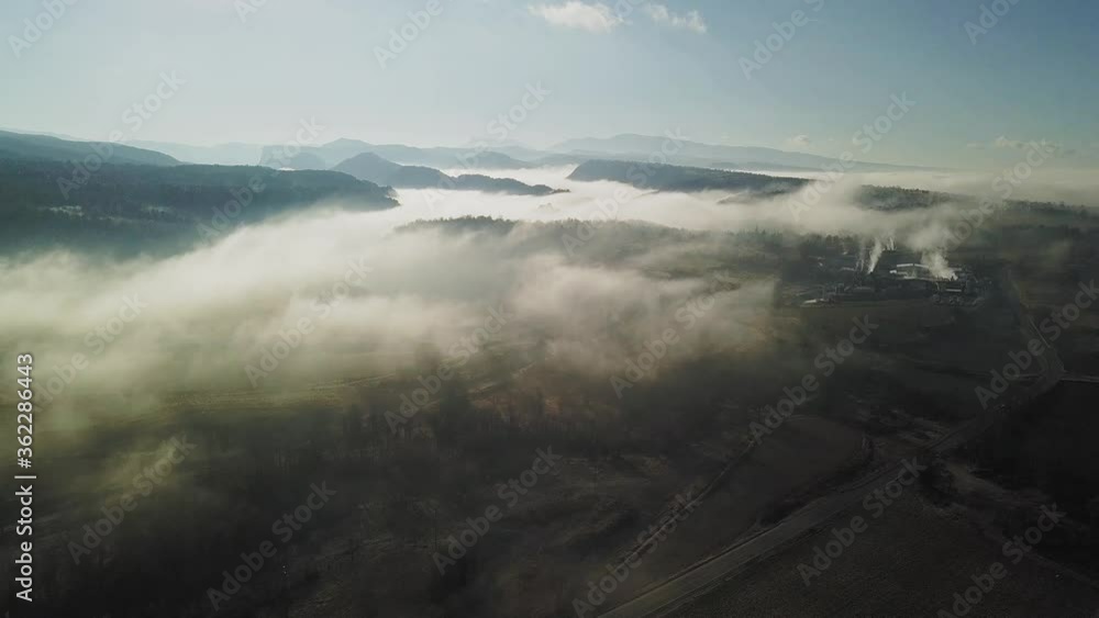 Aerial of clouds of fog over rural area with mountain silhouettes in background
Aerial of clouds of fog over rural area with mountain silhouettes in background
