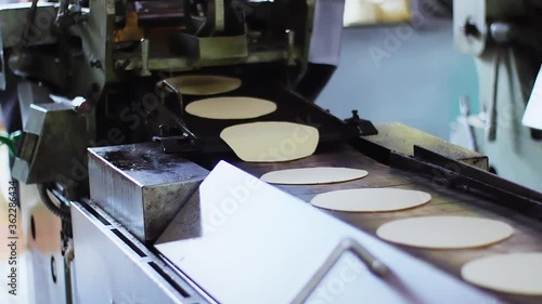 Uncooked tortillas in a conveyor belt photo