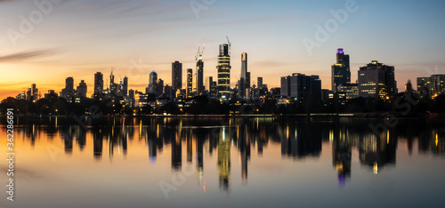 The reflections of the melbourne city skyline at dusk in the still water of albert park lake © TristanBalme