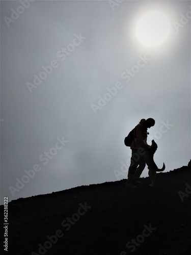 Man on a mountain top playing with a dog